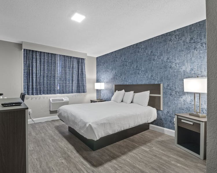 Bright guest room with bed, work desk, television, and storage